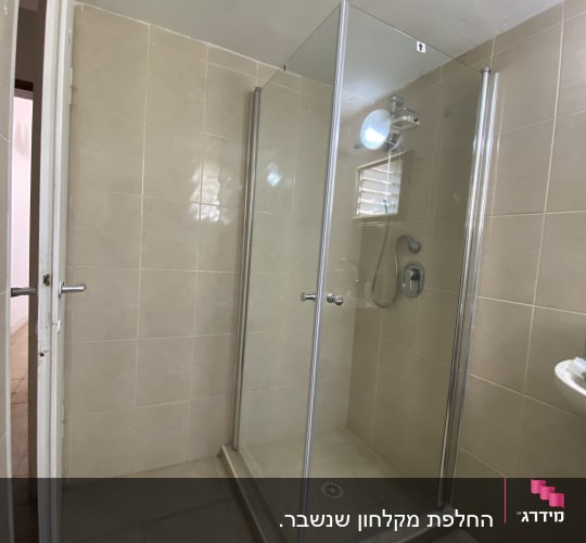 מקלחון זכוכית עם ראש מקלחת וקירות אריחים